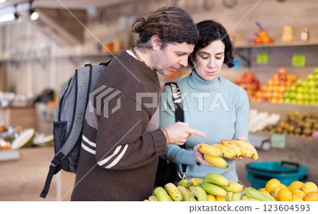 Couple man and woman choosing bananas in vegetable shop Couple man and woman choosing bananas in vegetable shop 123604593