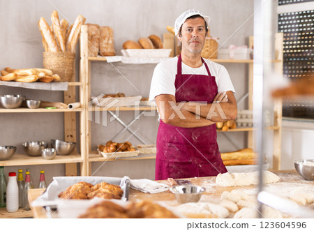 Caucasian man cook-baker stands at table in kitchen of bakery 123604596