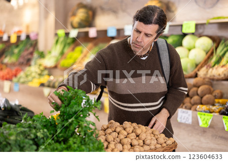 Adult man chooses parsley in vegetable shop Adult man chooses parsley in vegetable shop 123604633