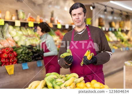 Adult man seller puts bananas on display 123604634