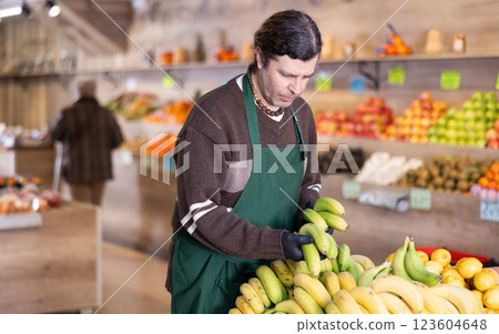 Man shop seller puts banana goods on display case 123604648
