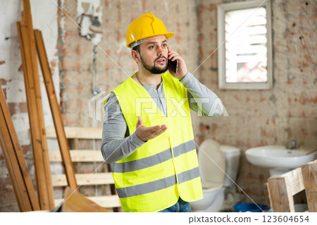 Young bearded civil engineer talking on phone at construction site Young bearded civil engineer talking on phone at construction site 123604654