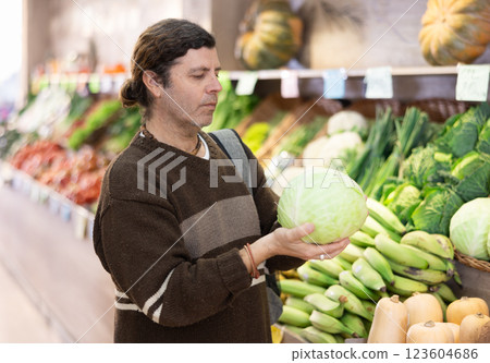 Adult man chooses cabbage in vegetable shop 123604686