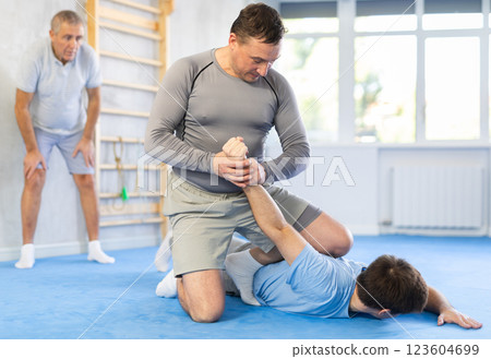 Man practicing painful armlock on male opponent at self defence training Man practicing painful armlock on male opponent at self defence training 123604699