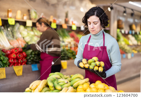 Woman shop seller puts banana goods on display case Woman shop seller puts banana goods on display case 123604700