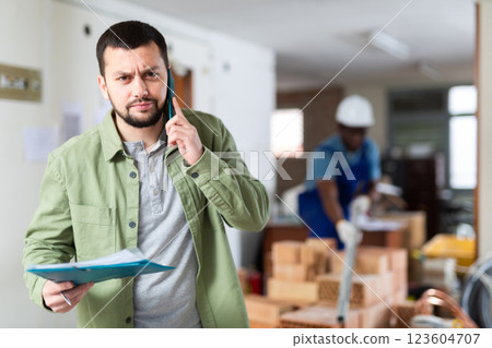 Irritated man talking phone at construction site 123604707