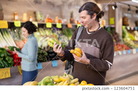 Adult man chooses bananas at vegetable shop Adult man chooses bananas at vegetable shop 123604751
