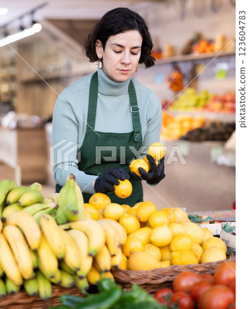 Adult woman seller puts lemons on display 123604783