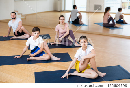 Family doing lord of the fishes pose in gym Family doing lord of the fishes pose in gym 123604798