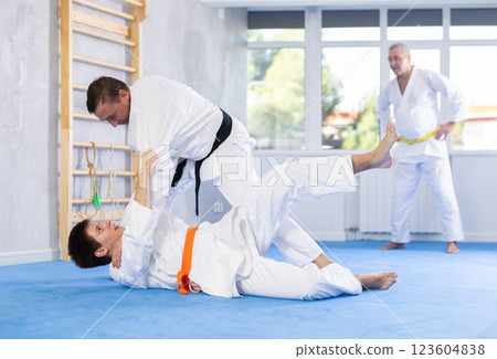 Men train to throw on the mat under the guidance of judo coach 123604838