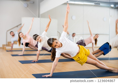 Girl doing side plank exercise during family training Girl doing side plank exercise during family training 123604867