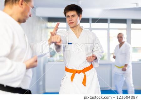 Young karate fighter working on punches in sparring with master at training Young karate fighter working on punches in sparring with master at training 123604887