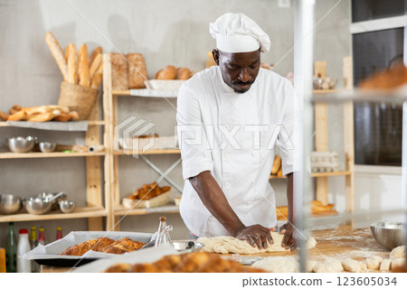 Experienced black baker kneading dough in artisan bakery 123605034