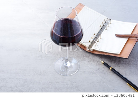 Image of a person writing a diary in a ring-type organizer while drinking red wine Image of a person writing a diary in a ring-type organizer while drinking red wine 123605481