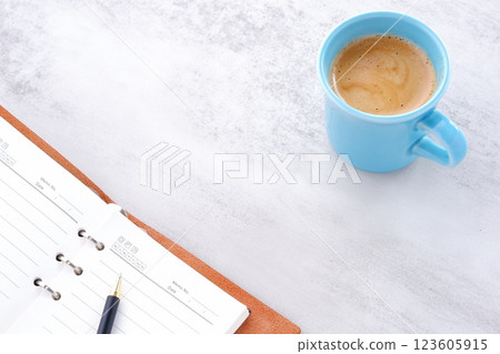 Image of a man working at his desk with a system organizer while drinking a cafe latte, a coffee with plenty of milk Image of a man working at his desk with a system organizer while drinking a cafe latte, a coffee with plenty of milk 123605915