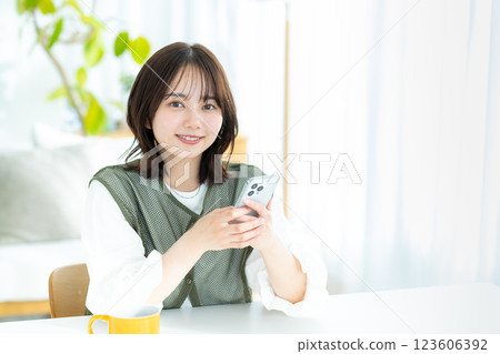 A young woman operating a smartphone in a room 123606392