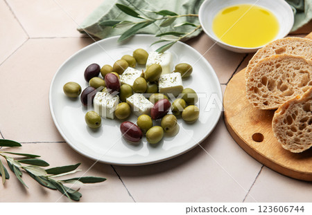 Fresh feta cheese with green and black olives, olive oil and bread on pink tiled table 123606744