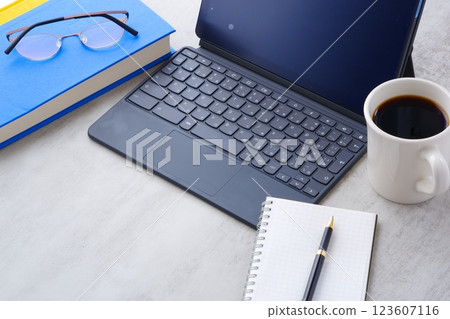 Image of a man doing desk work on a tablet with a keyboard connected while drinking coffee Image of a man doing desk work on a tablet with a keyboard connected while drinking coffee 123607116