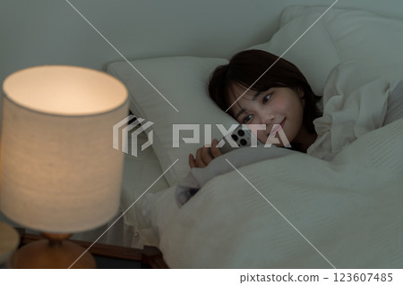 年輕女子在床上操作智慧型手機 123607485