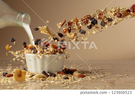 Muesli and milk in motion on a beige background. 123608523
