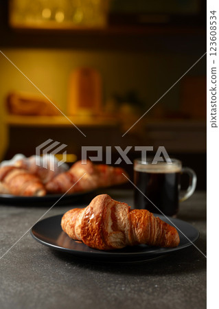 Fresh baked croissants and black coffee on a kitchen table. 123608534