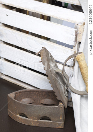 Old iron, heated by hot coals. Opened coal compartment. Standing next to a wooden box and linen cloth. 123608643