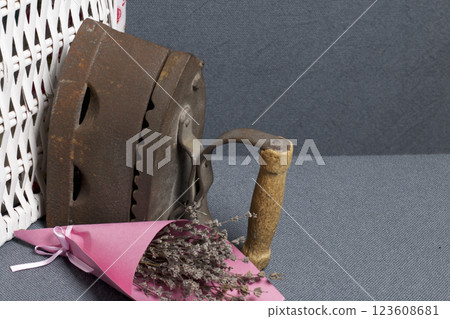 Old iron, heated by hot coals. Located near a wicker baskets. Near a bouquet of dried flowers. Old iron, heated by hot coals. Located near a wicker baskets. Near a bouquet of dried flowers. 123608681