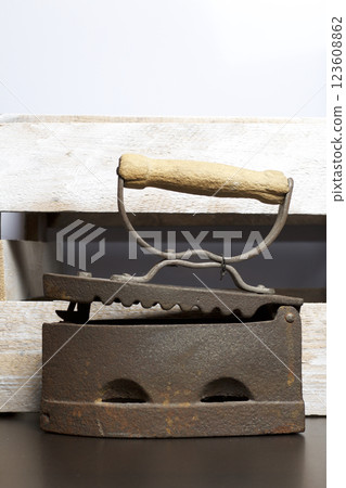 Old iron, heated by hot coals. Opened coal compartment. Located on the background of a wooden box. Old iron, heated by hot coals. Opened coal compartment. Located on the background of a wooden box. 123608862