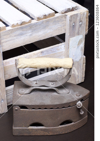 Old iron, heated by hot coals. Standing next to a wooden box. Old iron, heated by hot coals. Standing next to a wooden box. 123608864