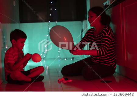 Mother and son preparing balloons for a party under colorful lights 123609448
