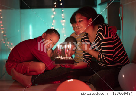 Happy family celebrating birthday with cake and candles at home Happy family celebrating birthday with cake and candles at home 123609484