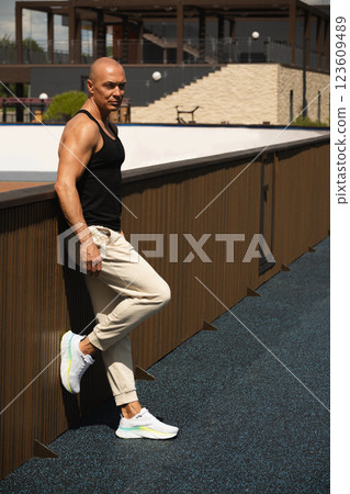 Athlete man or sports trainer in casual clothes standing, waiting and looking at camera. Outdoors. Vertical format. Summer. 123609489