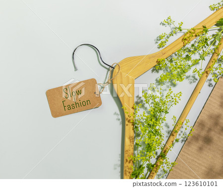 Slow fashion. Wooden hanger with tag with text Slow fashion with tree branch. Perfect visual for organic branding, sustainability concepts, slow fashion, or conscious lifestyle themes Slow fashion. Wooden hanger with tag with text Slow fashion with tree branch. Perfect visual for organic branding, sustainability concepts, slow fashion, or conscious lifestyle themes 123610101