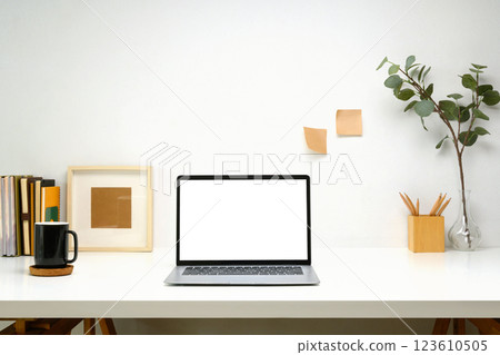 Laptop with blank screen, planner and a white coffee mug on white table, minimalist and modern workspace 123610505
