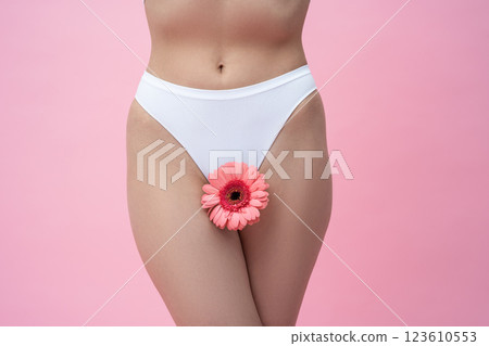 Unrecognizable woman in white panties with gerbera flower standing 123610553