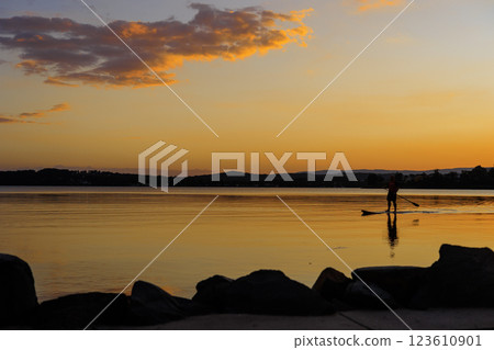 Sunset and the shadow of a man rowing a stand-up boat in Warners Bay, New South Wales Sunset and the shadow of a man rowing a stand-up boat in Warners Bay, New South Wales 123610901
