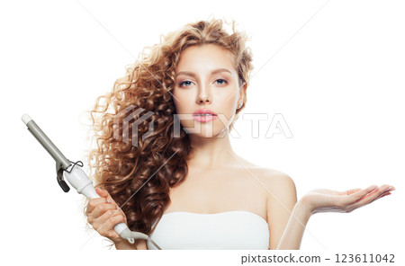 Isolated brown haired woman with shiny long curly hairstyle showing curling iron. Isolated brown haired woman with shiny long curly hairstyle showing curling iron. 123611042