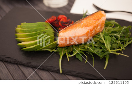 Baked sea trout fillet with fresh vegetables and herbs on black board Baked sea trout fillet with fresh vegetables and herbs on black board 123611195