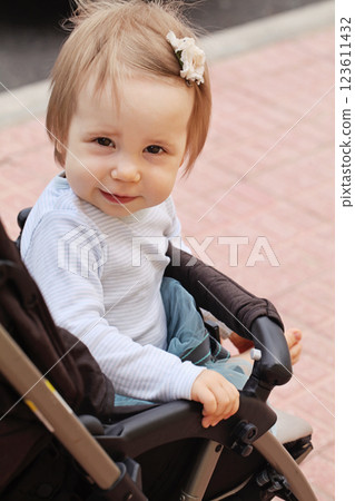 Beautiful little smiling baby girl sitting in pram, outdoors summer portrait Beautiful little smiling baby girl sitting in pram, outdoors summer portrait 123611432