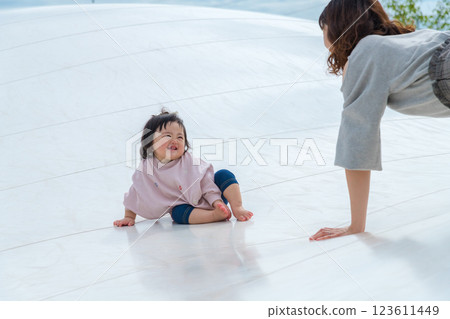 [Mother and infant sitting on giant playground equipment] 123611449