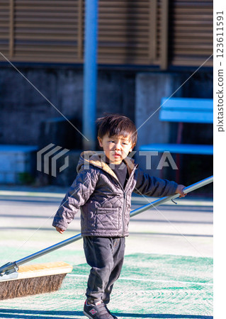 Boy maintaining tennis court, brushing 123611591