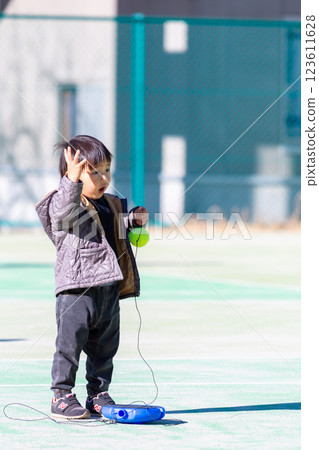 Boy playing on tennis court 123611628