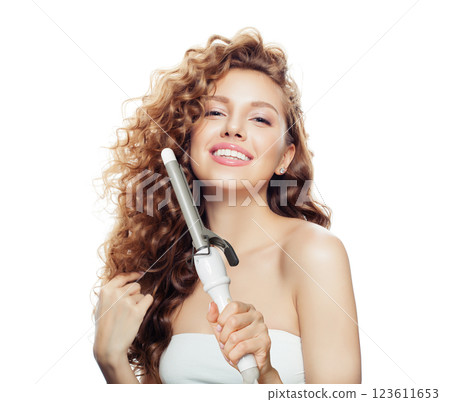 Happy brunette model using curling iron on white background. Coiffure, beauty salon and hair styling Happy brunette model using curling iron on white background. Coiffure, beauty salon and hair styling 123611653
