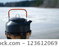 Metal small kettle boiling on gas burner in nature at campsite in winter. 123612069