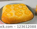 Delicious cooked just baked tangerine biscuit cake rotating on plate on kitchen. 123612088