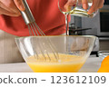 Pastry chef woman hands cooking pouring oil into batter in glass bowl. 123612109