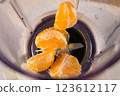 Tangerine pieces falling into blender to cook filling for pie on kitchen. 123612117