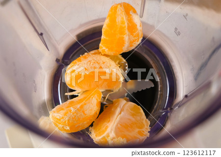 Tangerine pieces falling into blender to cook filling for pie on kitchen. Tangerine pieces falling into blender to cook filling for pie on kitchen. 123612117
