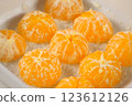 Pastry chef cooking pie placing peeled mandarin orange halves in baking dish. 123612126