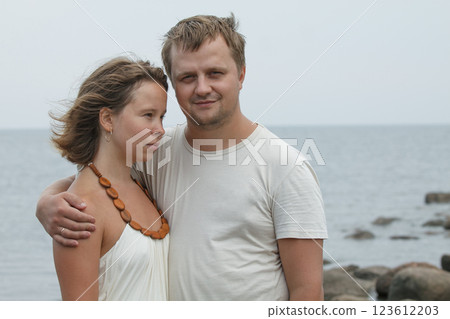 Portrait of young couple standing by sea Portrait of young couple standing by sea 123612203